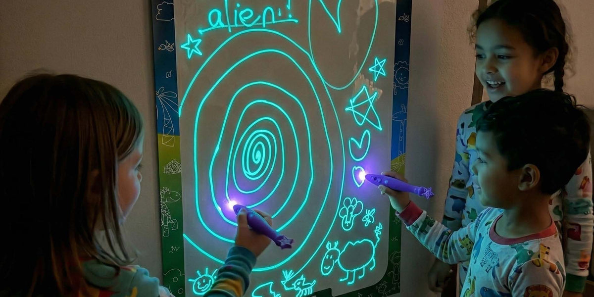 Children drawing with light pen on glow panel